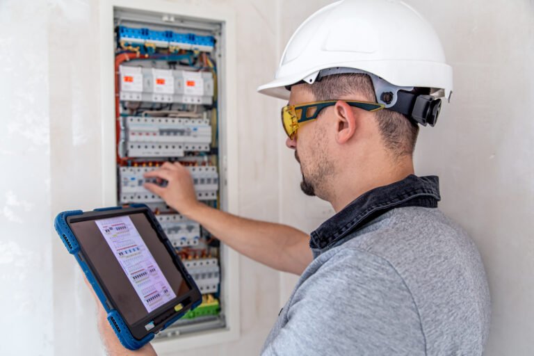 Electrical technician looking focused while working in a switchboard with fuses